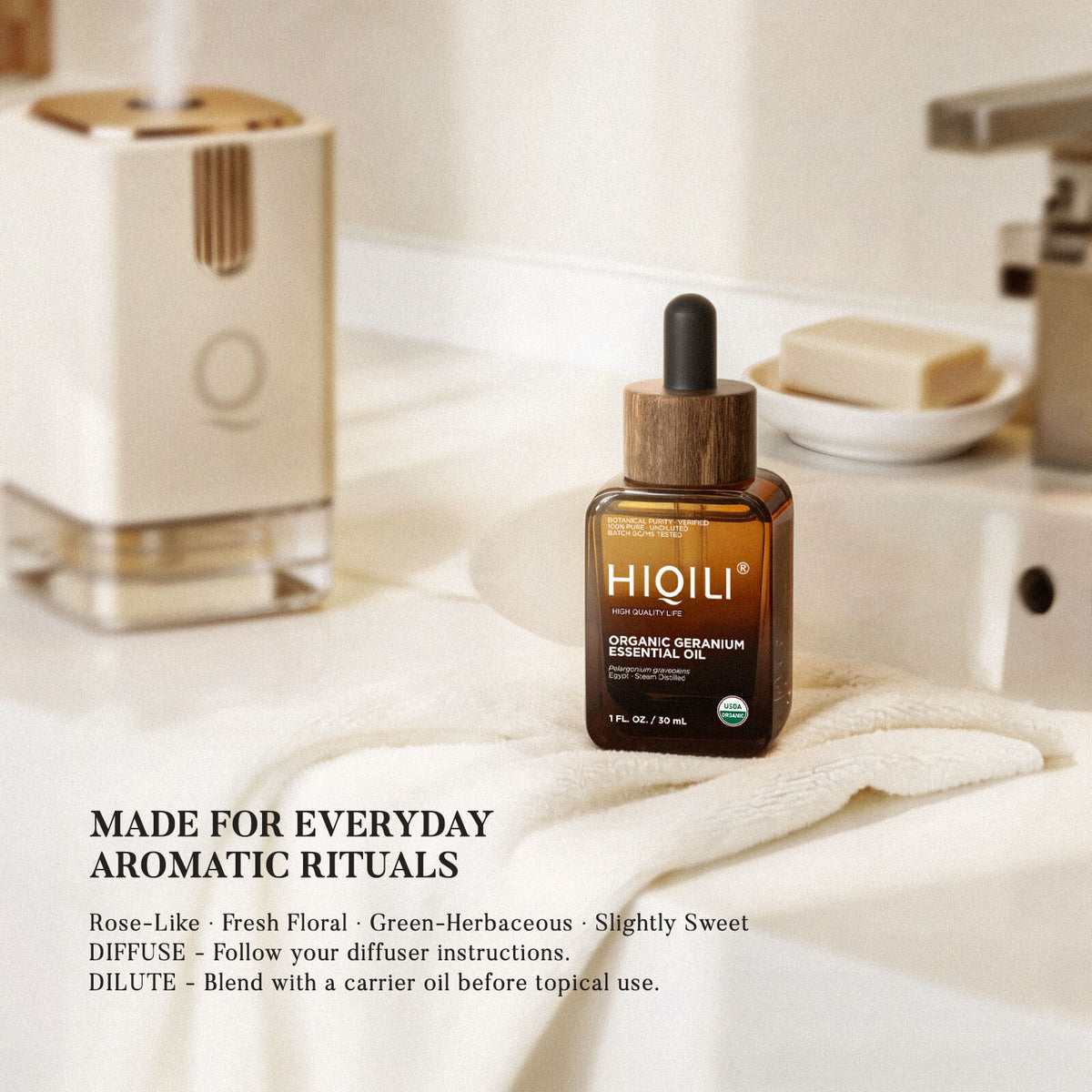 HIQILI organic geranium essential oil on a bathroom shelf beside a roller bottle and a soap dish
