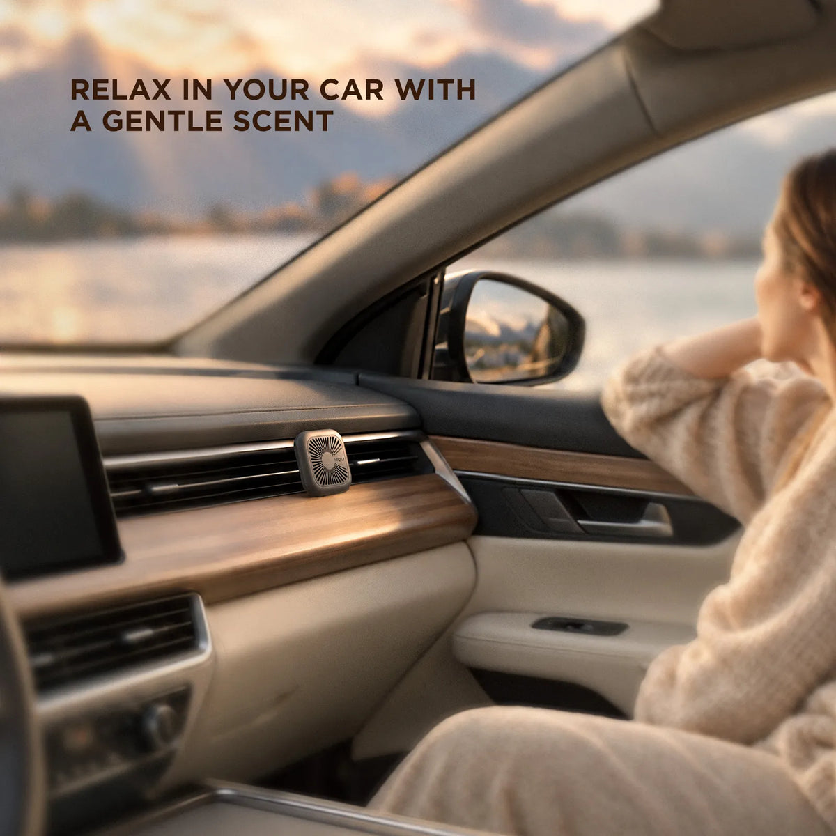 Charcoal gray car scent diffuser on a wood dash vent at sunset, with a driver relaxing in the passenger seat