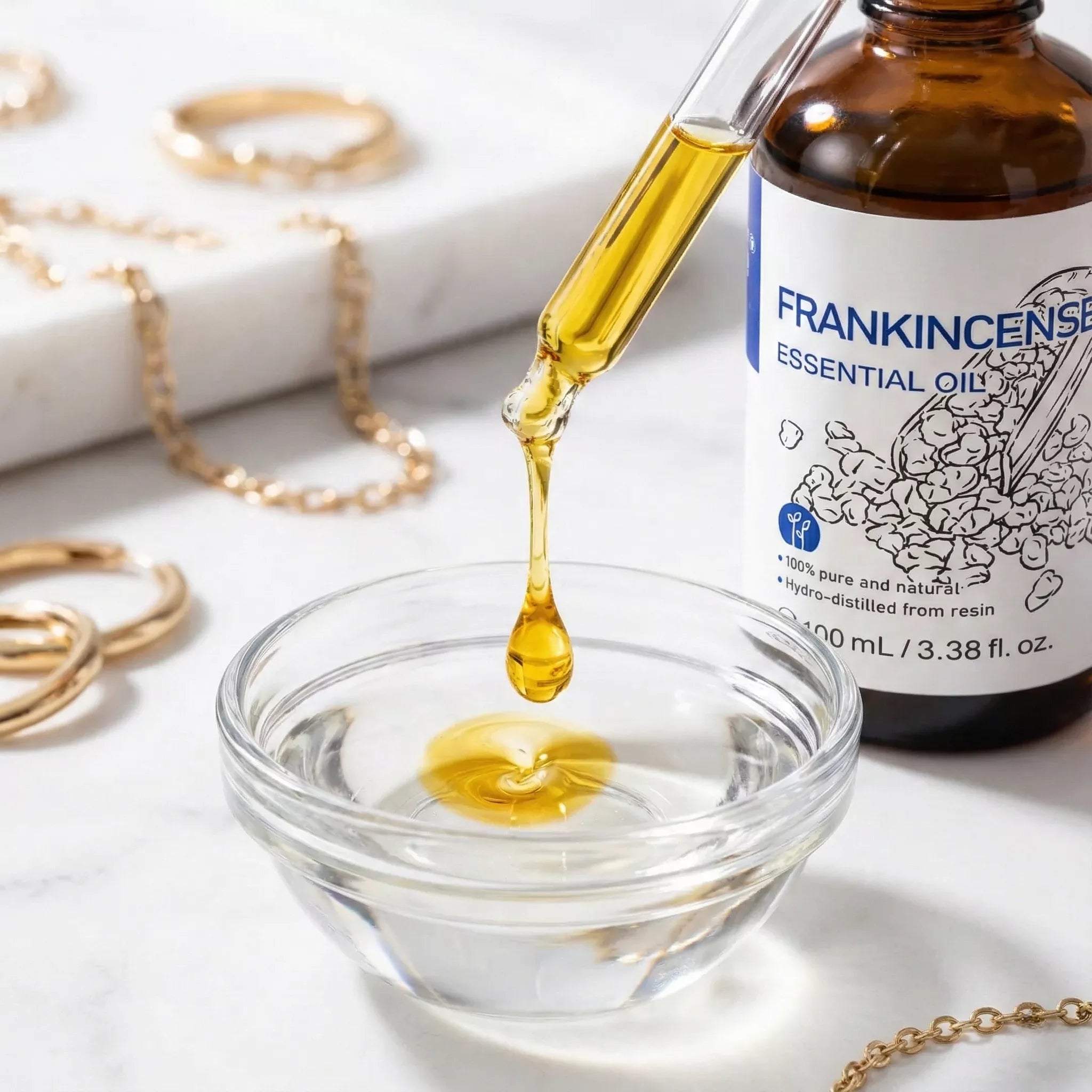 Mixing gold Frankincense Essential Oil into a face serum for anti-aging skincare routine on a marble vanity.