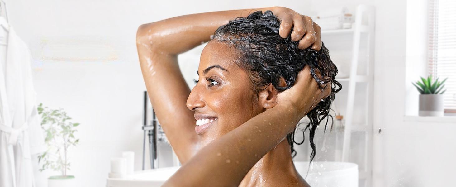 Smiling woman massaging pure lavender essential oil into her scalp to soothe dryness, nourish hair fibers, and promote healthy, fuller-looking hair.