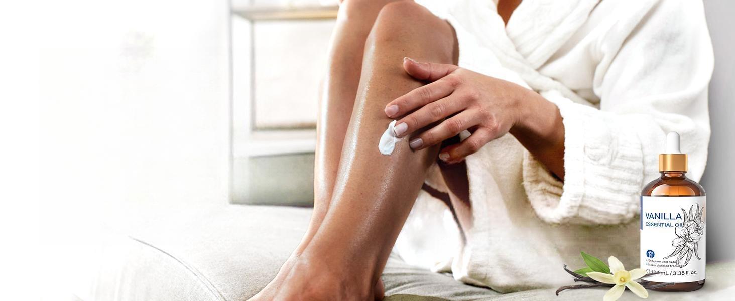 Woman applying a custom DIY blend of unscented body lotion and pure vanilla essential oil to her legs for deep moisturizing and soothing skin care.