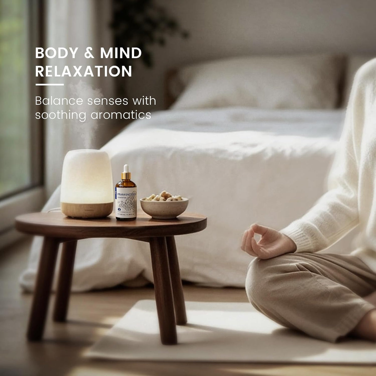 Woman meditating beside a diffuser using HIQILI Frankincense Essential Oil