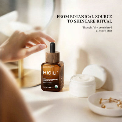 Hands unscrewing the dropper of a HIQILI organic geranium essential oil bottle beside a cream jar