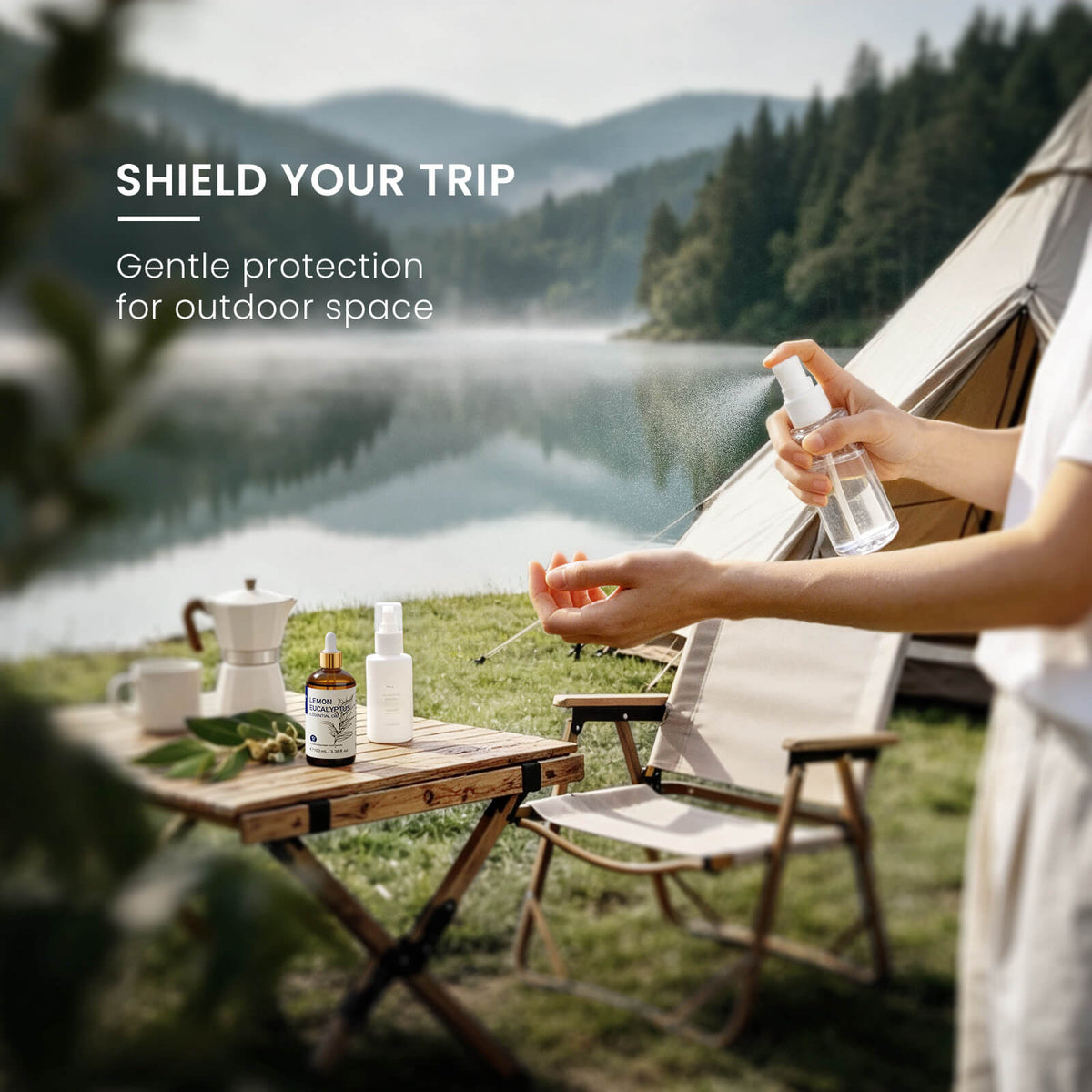 Person using an outdoor mist spray beside HIQILI Lemon Eucalyptus Essential Oil at a lakeside campsite.