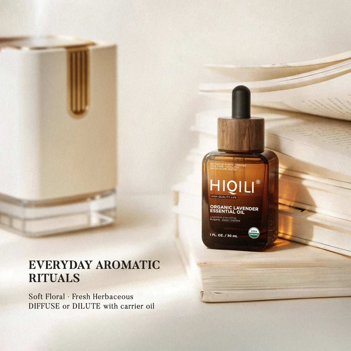 HIQILI organic lavender essential oil beside a diffuser and stacked books, highlighting its soft floral and fresh herbaceous aroma