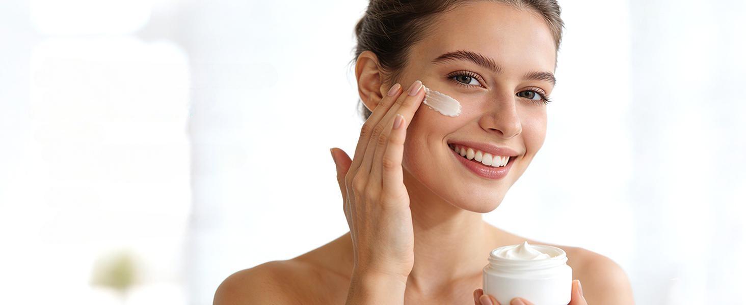 Smiling young woman applying a soothing blend of face cream and pure tea tree essential oil for a healthy, radiant, and clear complexion.